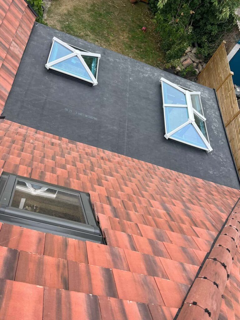 This is a photo taken from the roof ridge looking down a tiled pitched roof on to a flat roof. Works carried out by LJ Roofing Freshbrook